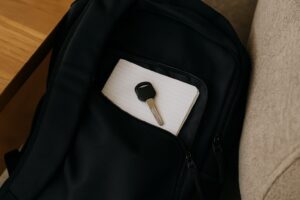 開いた黒いバックパックがソファの上に置かれている。中には文房具や日用品が散らばっており、鍵が見つからなさそうな雰囲気。