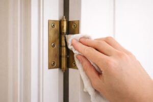 ドアの蝶番まわりの汚れを布で拭き取っている様子