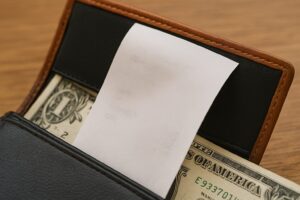 財布の中から出ているレシートが、紙幣と一緒に挟まれている様子
