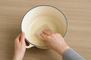 ホーロー鍋の内側を、布で丁寧に拭いてお手入れしている様子