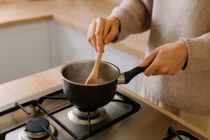 片手鍋で調理中の手元。木べらでかき混ぜながら加熱する様子