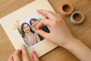 マスキングテープで写真を色紙に貼っている手元の様子。写真はカップルが笑顔で写っている