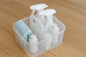 洗面台下の空間を活用した、透明ケースに整理された掃除道具の収納例
