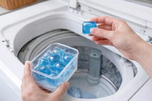 洗濯機の上で洗剤を手に取り、使用前後の扱いを確認している様子