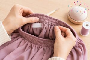 縫い付けられたウエストゴムを部分的に調整するため、針と糸で縫い直している手元