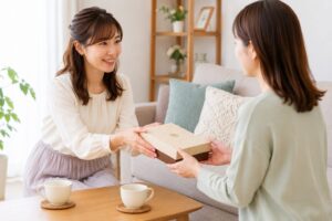 リビングで手土産のお菓子を両手で渡し、相手が受け取っている様子